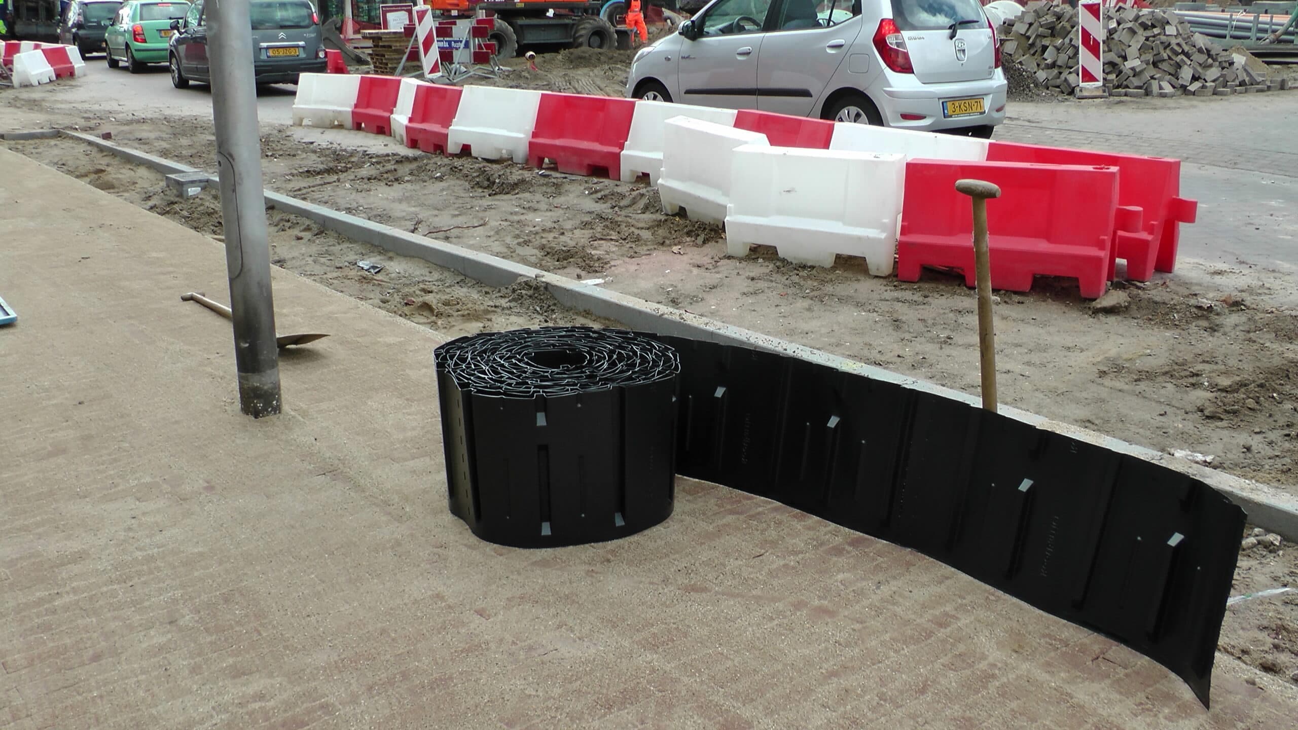 Straatwerf in een woonstraat, graafmachine en werfafzetting bij de plaatsing van wortelgeleiding